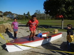 Pollution Solution Obstacle Course participants - child jumping off wooden boat in center