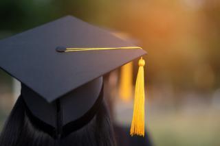Photograph of a student standing with a graduation cap