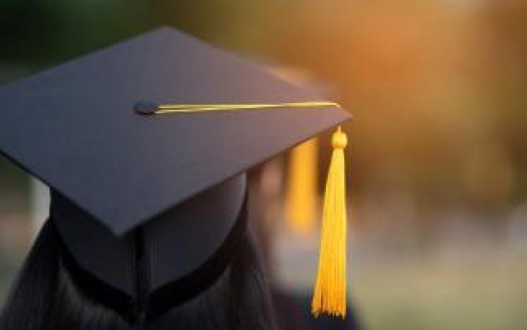 Photograph of a student standing with a graduation cap
