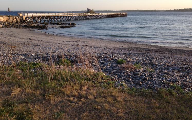 Image of Fort Foster Park featuring the sandy beach and long pier extending into the ocean