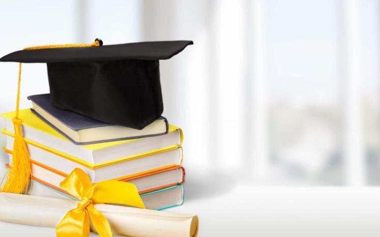 Image of a graduation cap and a diploma on a stack of colorful books